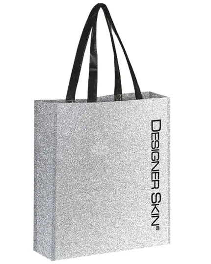 Silver glitter tote bag with black handles featuring the Designer Skin name in black letters positioned vertically along the left front side.