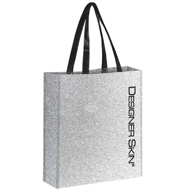 Silver glitter tote bag with black handles featuring the Designer Skin name in black letters positioned vertically along the left front side.