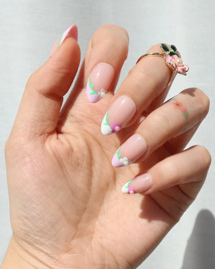 A touch of ooh la la. The Fleur de Magnolia press-ons bring effortless French charm to your fingertips! Inspired by the magnolia flower and the timeless elegance of a Parisian garden, these press-on nails combine soft pink bases with crisp white French tips, adorned with delicate floral accents and fresh green leaves. 