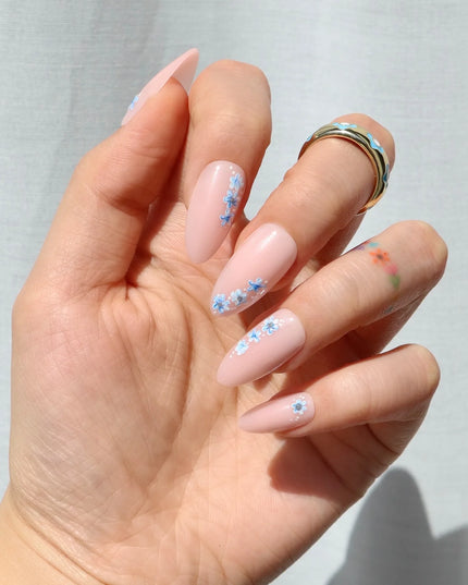 A little bloom goes a long way with Sprigs of Blue. These press-on nails embrace delicate floral accents without overwhelming your style. Soft blue petals scatter over a neutral base, creating a design that’s light, refined, and effortlessly elegant. The medium almond shape keeps things polished, while the glossy finish enhances the fresh, minimalist appeal. Whether you're elevating an everyday look or adding a subtle floral flourish, Sprigs of Blue is proof that simplicity blooms beautifully.