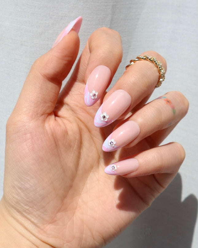 Like daydreams of Paris, Floral Reverie sweeps you away to a world of soft elegance and effortless charm. Blended pastel swirls on classic French tips mimic the watercolor skies over the Seine at dawn, while dainty floral accents add a touch of je ne sais quoi. The medium almond shape offers a refined silhouette, and the glossy finish captures the light like a Parisian café window on a sunny morning.